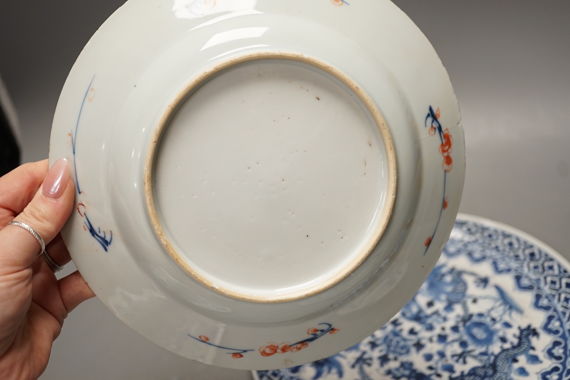 Four Chinese 18th century plates and a late 19th century blue and white dragon plate, largest 24cm diameter